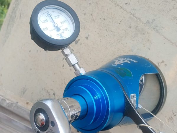 Cilindro hidráulico de tração com manômetro analógico e catraca montados sobre base de concreto
